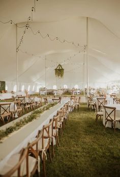 a large tent with tables and chairs set up for a wedding or other function in the grass