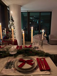 the table is set for christmas dinner with candles and napkins on top of it