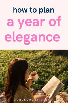 a woman sitting on the grass reading a book and holding a cup in her hand