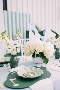 the table is set with white flowers and green plates