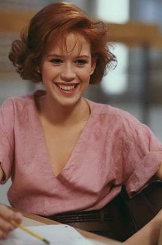 a woman sitting at a table with a piece of paper in her hand and smiling