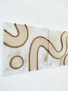 two pieces of art made out of rope and jute, hanging on the wall