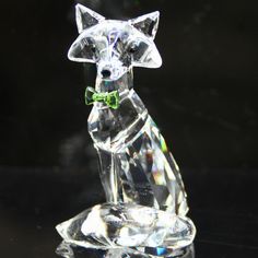 a crystal dog figurine with a green bow on it's collar sitting on a black surface