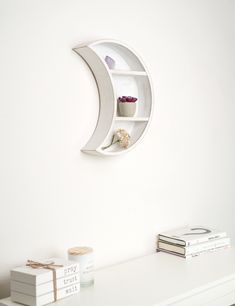 a white shelf with some books on it and a moon shaped shelf in the corner