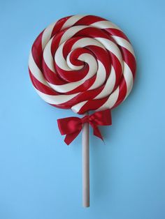 a large red and white lollipop on a stick with a bow around it