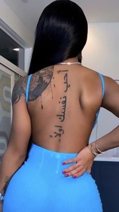 a woman with tattoos on her back standing in a kitchen