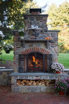 an outdoor fireplace is shown with flowers and potted plants