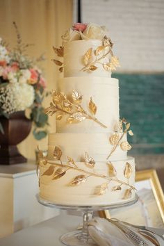 a white wedding cake with gold leaves on it