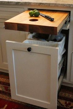 a cutting board and knife on top of a cabinet in a kitchen with white cabinets