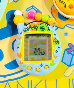 an electronic toy sitting on top of a colorful tablecloth covered floor next to other toys