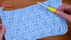 someone is crocheting the edges of a blue knitted dishcloth with a yellow plastic needle