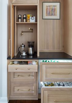 an open cabinet in a kitchen with coffee pots and tea kettles on the counter