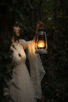 a woman holding a lantern in the woods