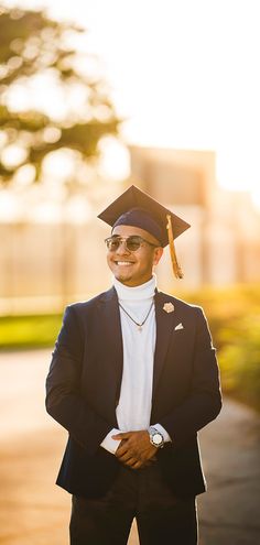 a man in a graduation cap and gown is standing on the sidewalk with his arms crossed