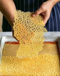 a person is sprinkling some kind of yellow substance into a metal pan on top of a table