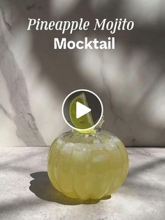 a glass bottle filled with liquid sitting on top of a marble counter next to the words pineapple mojito cocktail