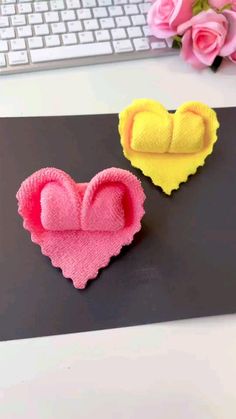 two felt hearts sitting on top of a computer desk next to a keyboard and pink roses