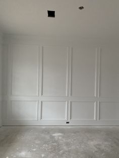 an empty room with white paneling on the walls