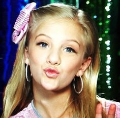 a woman with long blonde hair holding a pink comb in front of her face and making a funny face