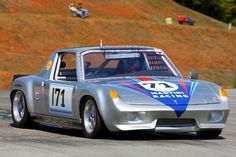 a silver sports car driving down a race track