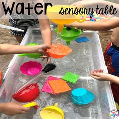 children are playing with water and sand in a tray