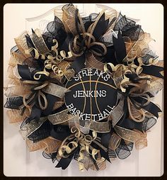 a basketball wreath is hanging on the front door with black and gold ribbon around it