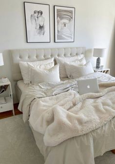 a bed with two pictures above it and a laptop computer on top of the bed