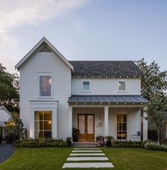 a white house with steps leading up to the front door and side porch, along with grass