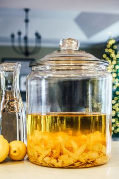 a glass jar filled with liquid sitting on top of a counter next to lemons