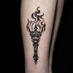 a black and white tattoo on the leg of a woman with a torch in it