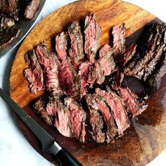 sliced steak on a cutting board next to a skillet