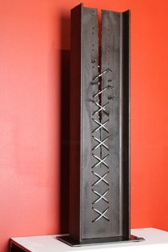 a tall metal object sitting on top of a white table next to a red wall