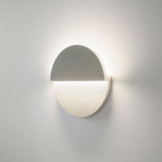 a white light that is on the side of a wall with a circular object in front of it