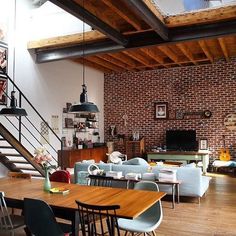 a living room filled with furniture and a wooden table in front of a brick wall