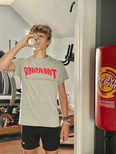 a young man drinking from a can in a gym