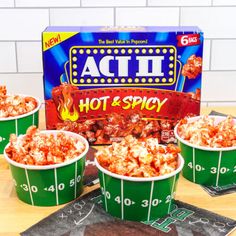 three green buckets filled with hot and spicy popcorn next to a box of acti