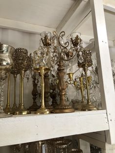 a shelf filled with lots of glass vases and candle holders on top of it