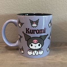 a purple coffee mug with an image of a cat and other cats on it, that says kuromi