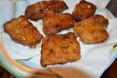 some fried food sitting on top of a white paper towel in a glass bowl with napkins