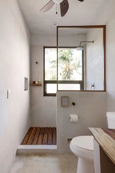 a bathroom with a ceiling fan and wooden flooring