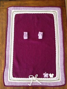 a purple crocheted blanket with two white squares on it