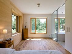 a bedroom with wood flooring and large windows overlooking the yard outside in front of it