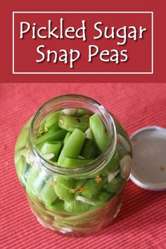 pickled sugar snap peas in a glass jar on a red tablecloth with the words pickled sugar snap peas