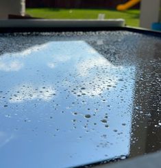 raindrops on the windshield of a car in front of a backyard with a slider