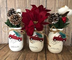 three mason jars decorated with pine cones, poinsettis and red car ornaments