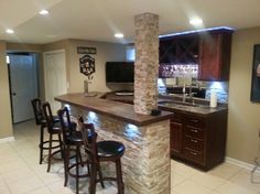 a kitchen with a bar and stools next to the counter top that has wine glasses on it