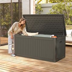 a woman standing next to an outdoor storage box on a deck with the lid open