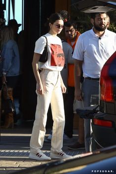 a woman standing on the side of a road next to a man