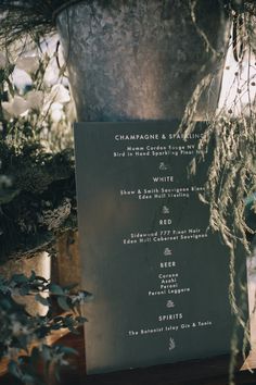 a menu sitting on top of a wooden table next to a potted plant with white flowers