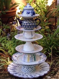 three tiered plates stacked on top of each other in front of plants and flowers